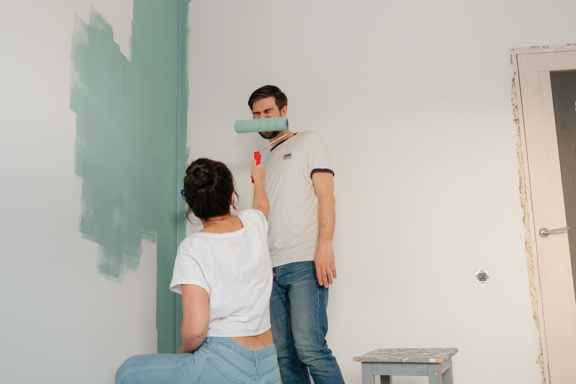 A couple collaborating to paint a room in light colors, focusing on teamwork and home improvement in Riverside, CA